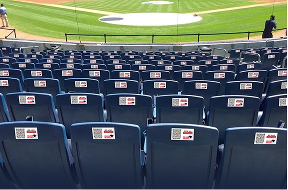 Real-world installation showing 33 ALERTS emergency alert decals installed on stadium seatbacks for instant security response