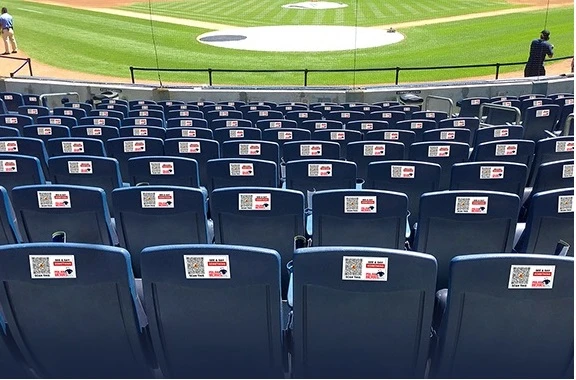 Real-world installation showing 33 ALERTS emergency alert decals installed on stadium seatbacks for instant security response